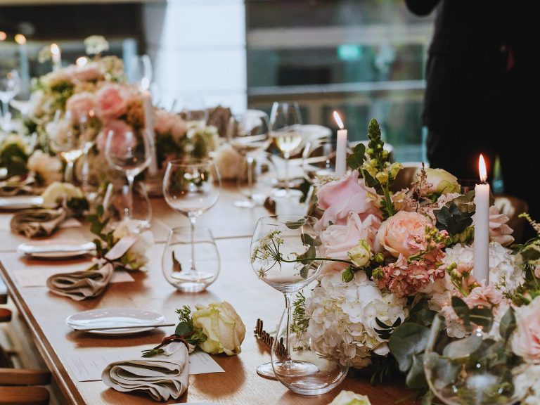 Long timber table with blush florals, tapered candles and linen napkins